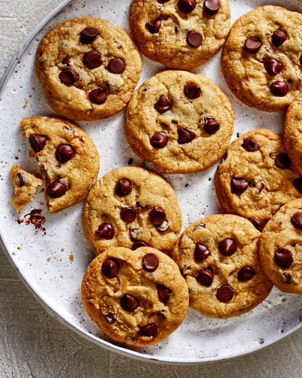 Chocolate chip cookies on a small platter, with one cookie partially eaten