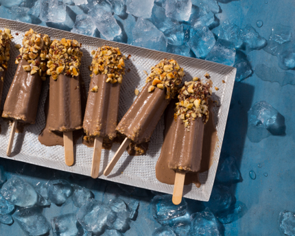 Chocolate Kulfi pops with crushed hazelnuts melting on a tray