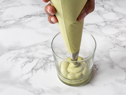 Piping matcha Irish cream mascarpone in a glass with a piping bag