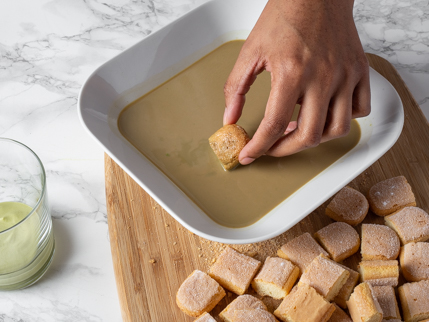 Dunking ladyfinger pieces in matcha-espresso mixture