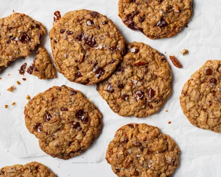 Cowboy cookies with chocolate chips, toffee bits, and pecans on wax paper