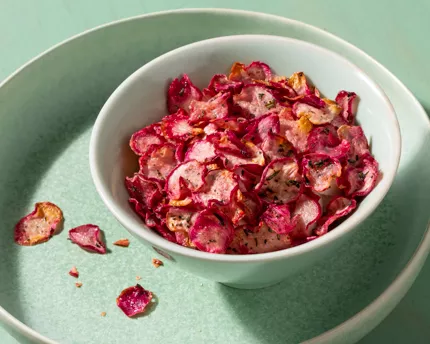 White bowl of rosemary radish chips on a green platter