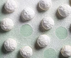 Snowball cookies on a green background, dusted with icing sugar