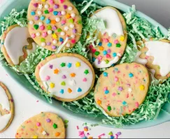 6 Easter egg cookies decorated with sprinkles and royal icing in a basket